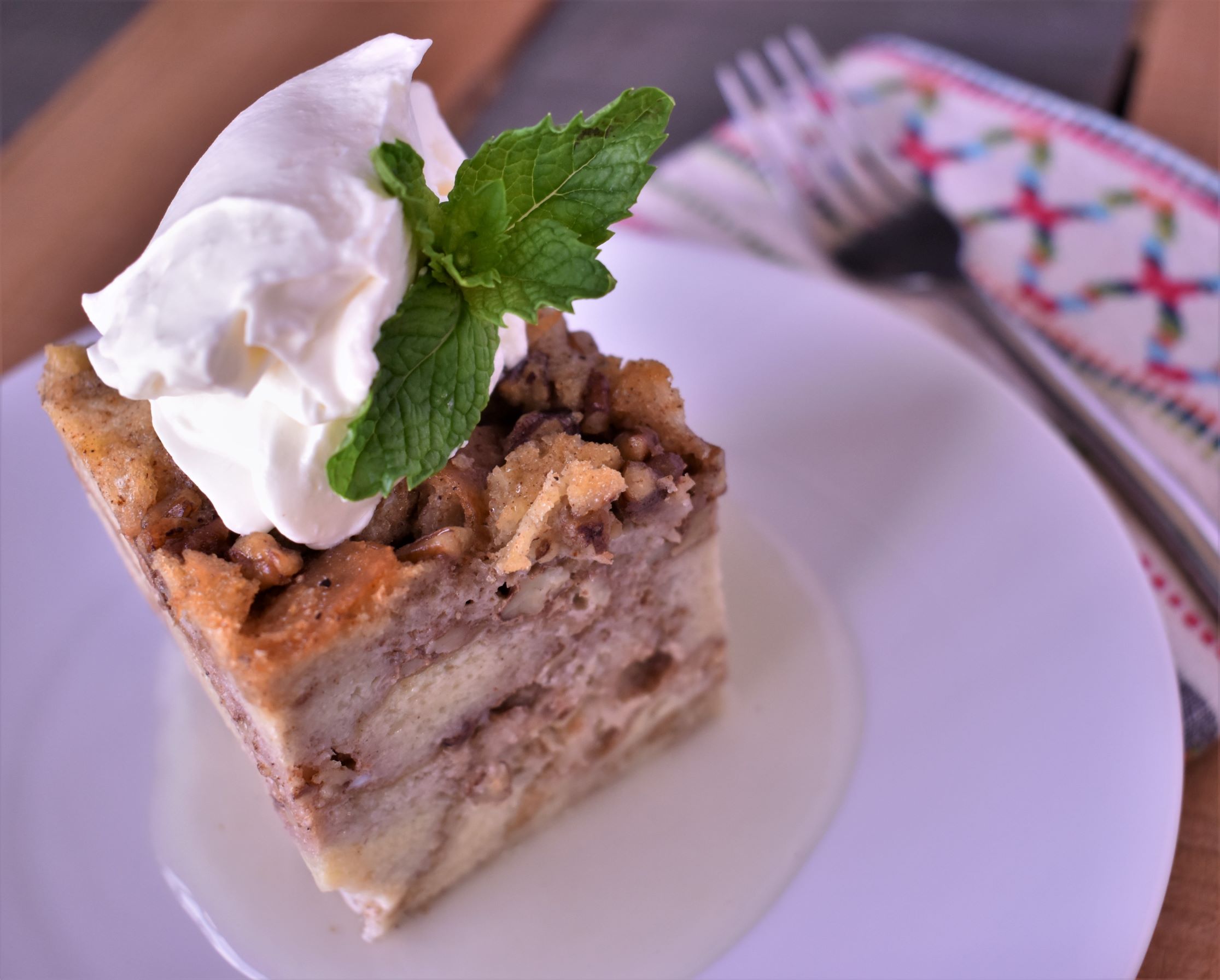 a piece of new orleans bread pudding with lemon sauce and a dallop of chantilly cream