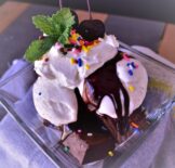 a dish of hot fudge brownie sundae with sprinkles and a cherry on top