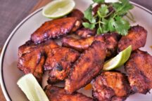 a plate full of chipotle mole wings with lime slices