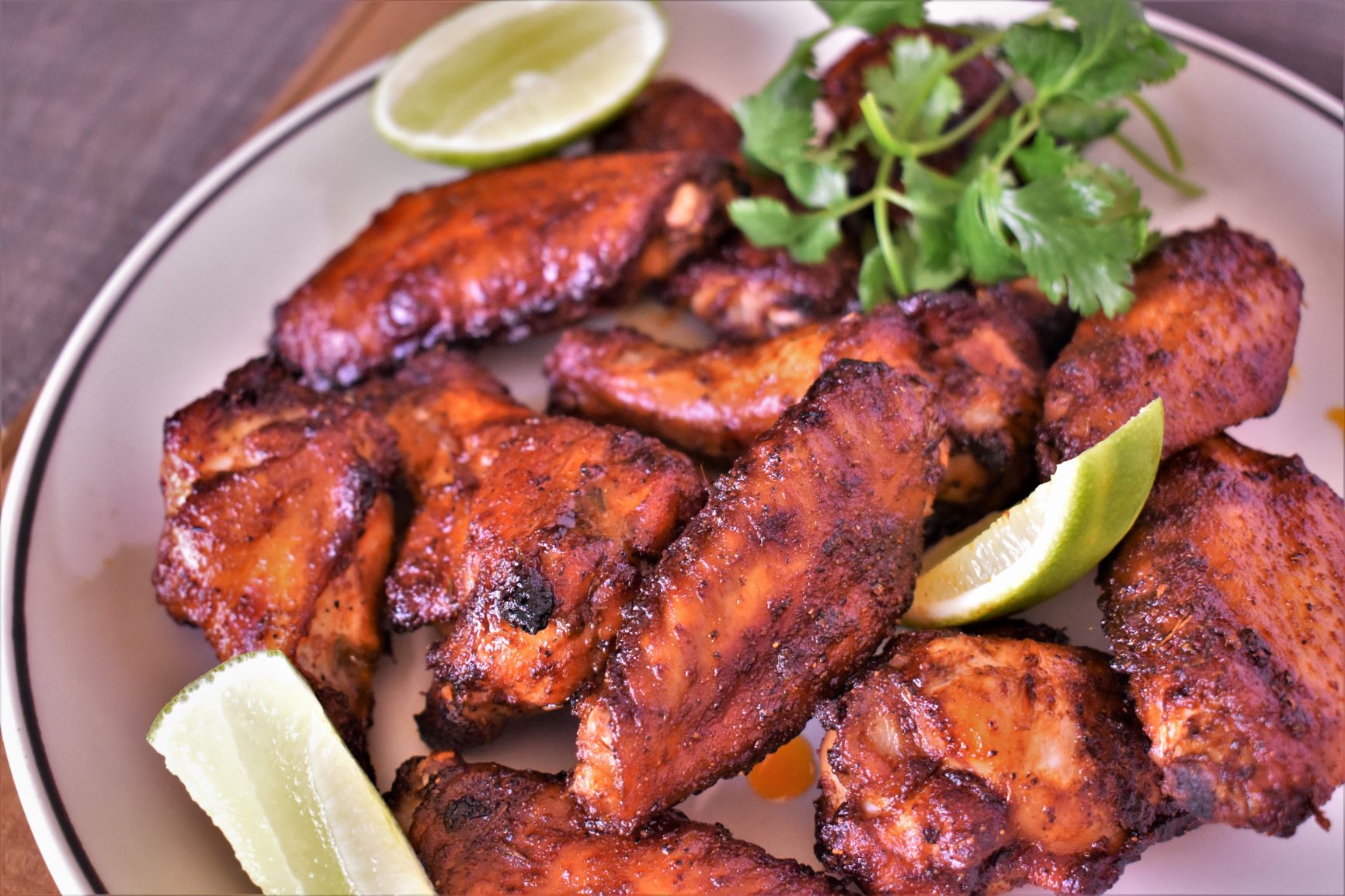 a plate full of chipotle mole wings with lime slices