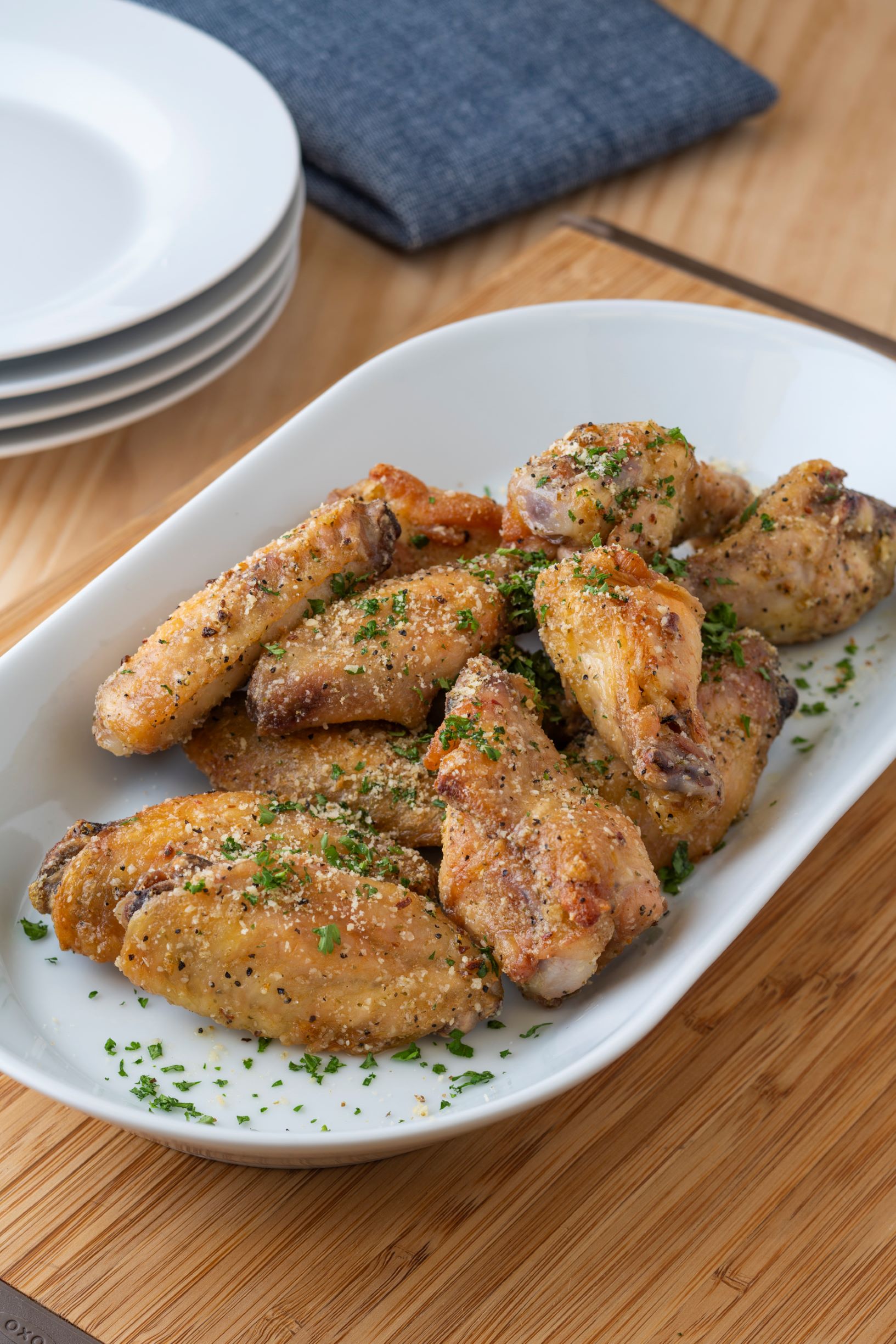 a plate of lemon pepper parmesan wings with basil on top