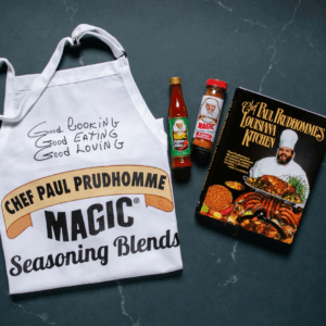 Chef Paul's birthday bundle which includes and apron that has chef paul's logo, chef paul's louisiana kitchen cookbook, a bottle of his magic pepper sauce and a container of blackened redfish magic