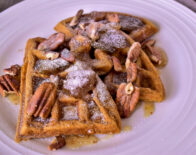 a close up of a plate of 3 sweet potato waffles with a buttery fig sauce on it
