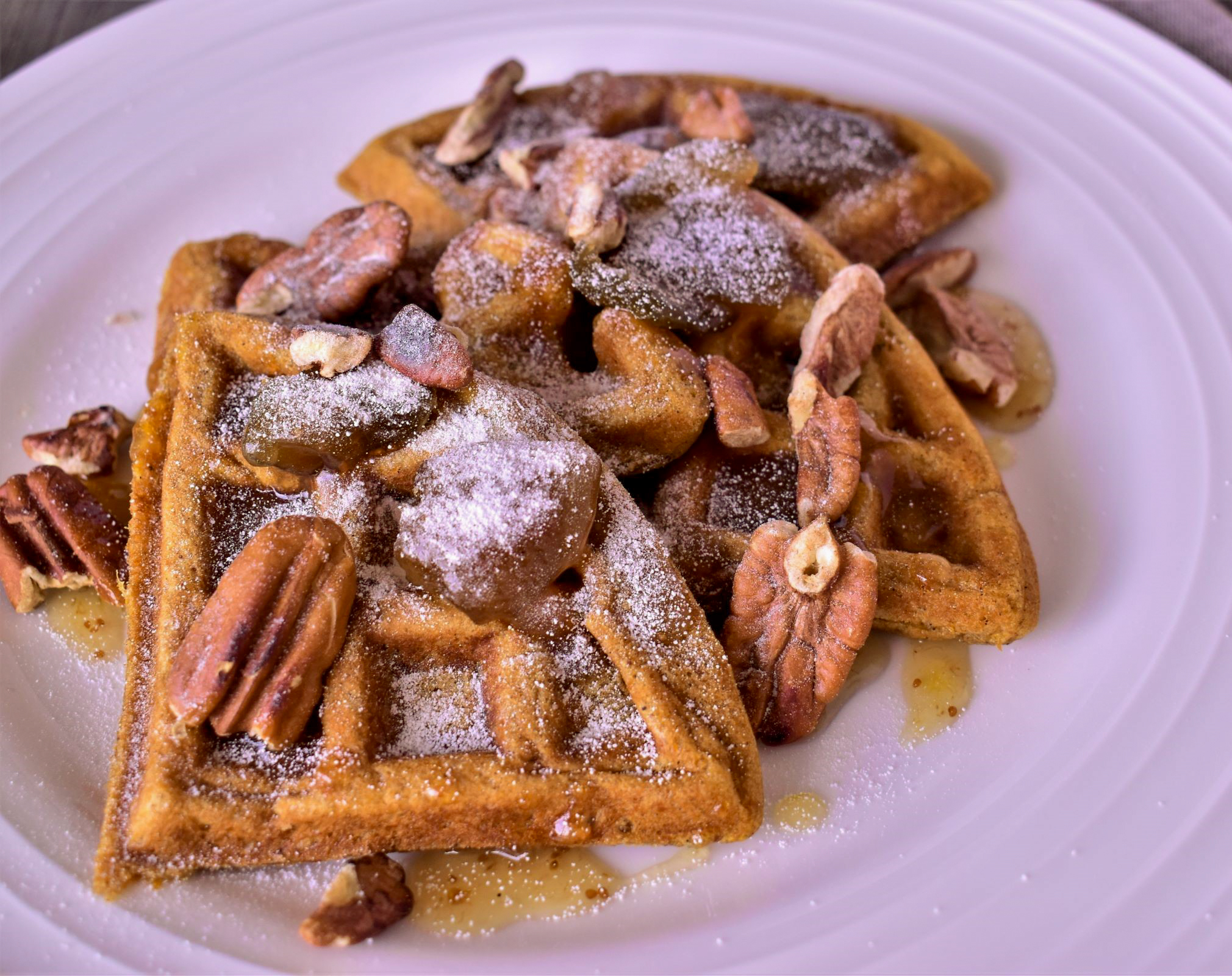 a close up of a plate of 3 sweet potato waffles with a buttery fig sauce on it