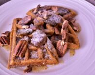 a close up of a plate of 3 sweet potato waffles with a buttery fig sauce on it