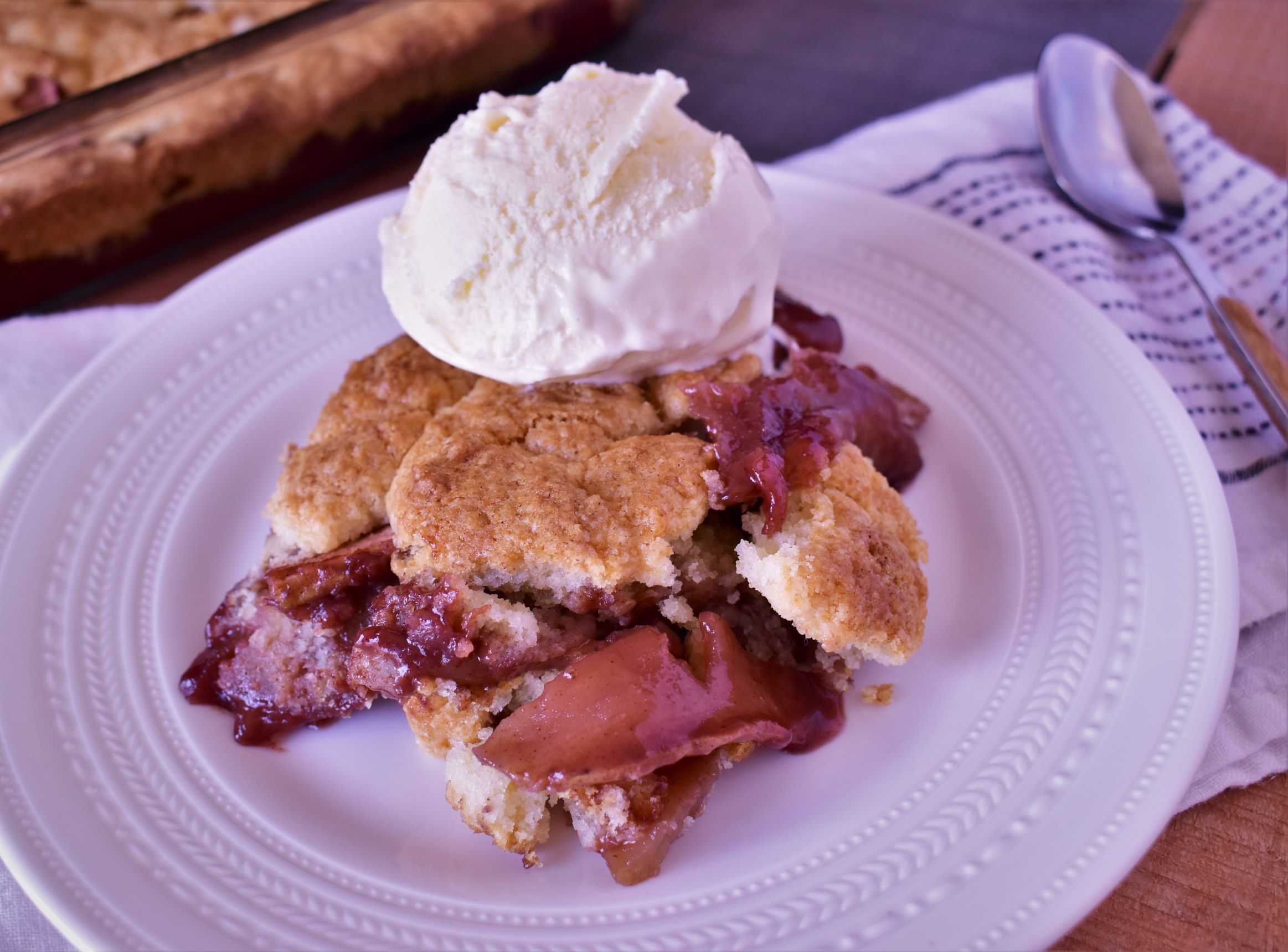 a piece of pomegranate and apple cobbler with a scoop of vanilla ice cream on top