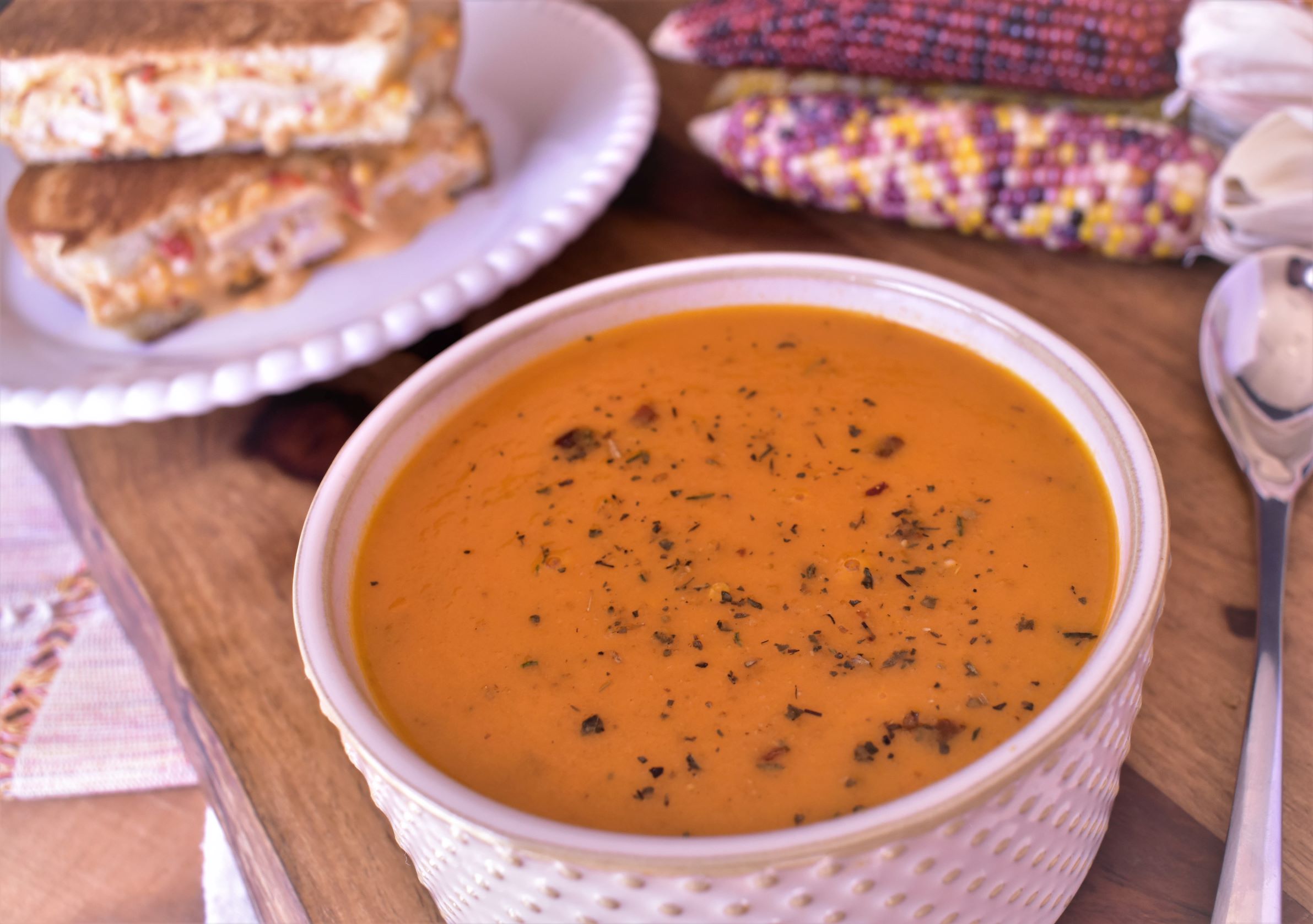 a bowl of roasted tomato cream soup next to a plate of grilled cheese sandwhiches