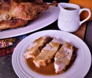 a plate of 3 pieces of roasted turkey with jalapeno gravy next to a container of gravy and the roaster turkey it came from