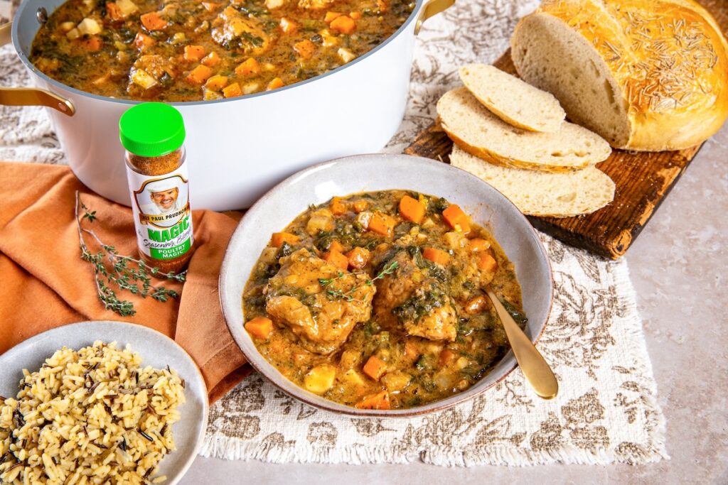 Turkey and fall vegetable stew in a bowl, with a bowl of wild rice, sliced rosemary bread, and a bottle of Chef Paul Prudhomme’s Poultry Magic.