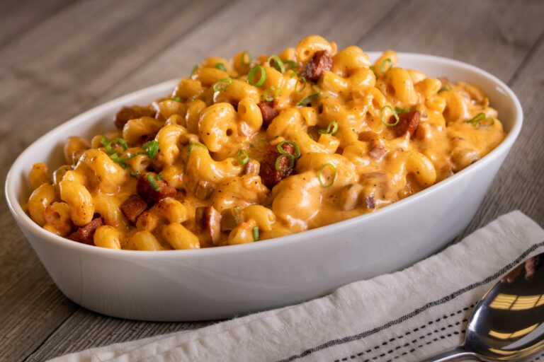a serving bowl of cajun mac and cheese with a sausage and green onions