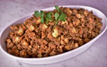 a serving dish of cornbread dressing with a garnish of basil on top