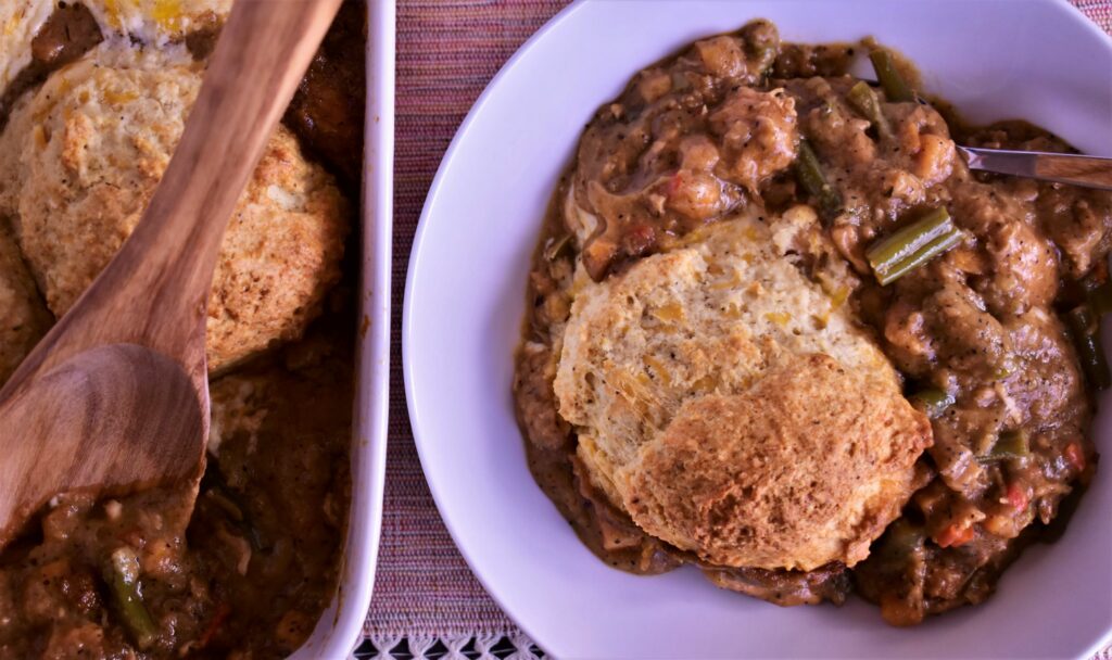 a plate of pot pie next to the serving dish of pot pie it came from