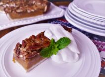 a piece of sweet potato pecan pie squares with a green garnish and a dallop of whipped cream