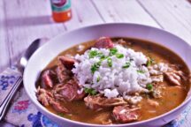 a bowl of 1 hour chicken and sausage gumbo topped with rice and green onions