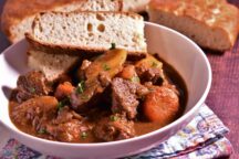 a bowl of beef and irsh stew with 2 pieces of bread