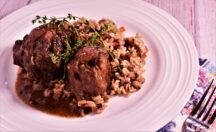 a plate of carribean coconut jerk oxtails with a side of dirty rice