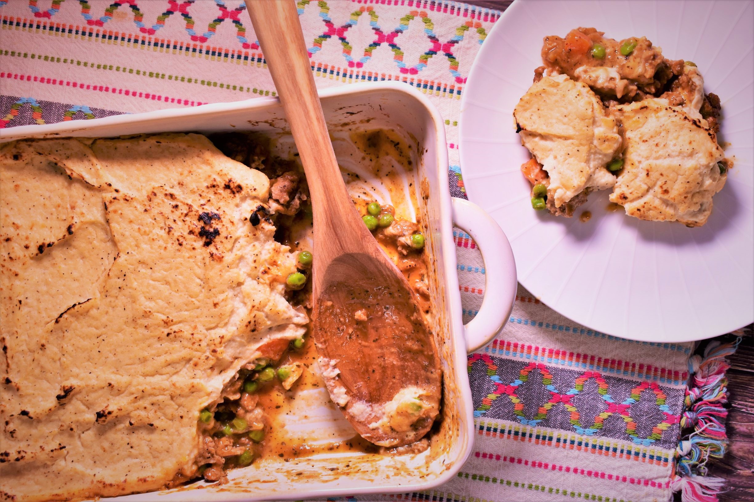 a piece of turkey cauliflower shepherds pie next to the half full container of shepherds pie