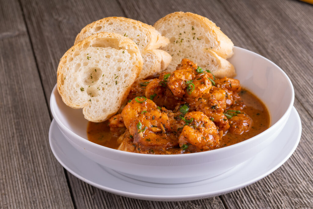 a bowl of bbq magic shrimp and 3 pieces of garlic bread