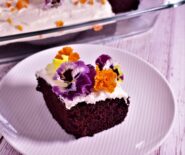 a piece of devil's food cake with a colorful flowery garnish next to the contain of devil's food it came from