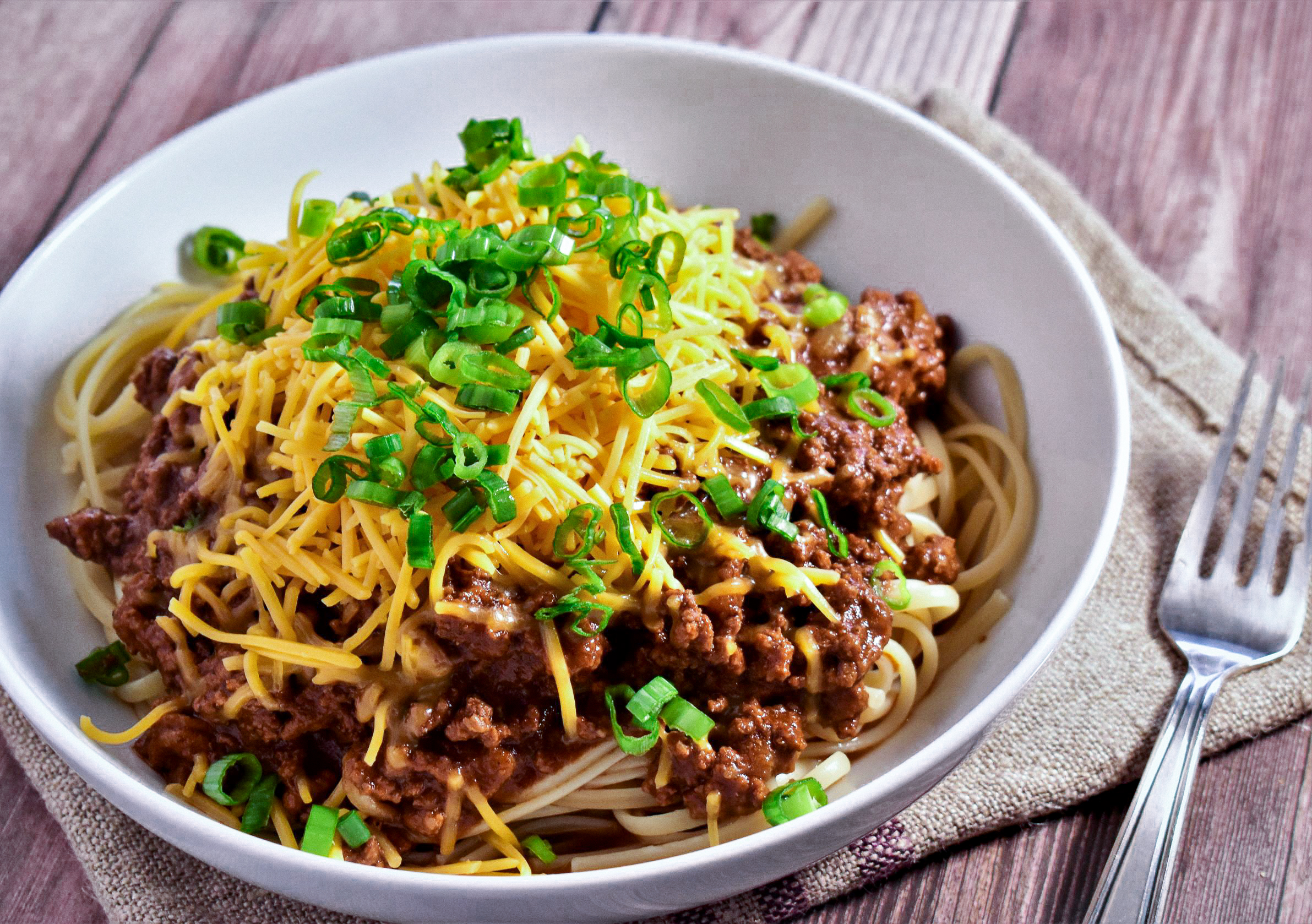 a bowl of cincinnati chili topped with green onions