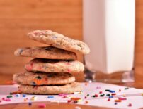 5 confetti snickerdoodle cookies stacked on top of each other with sprinkles scattered around them