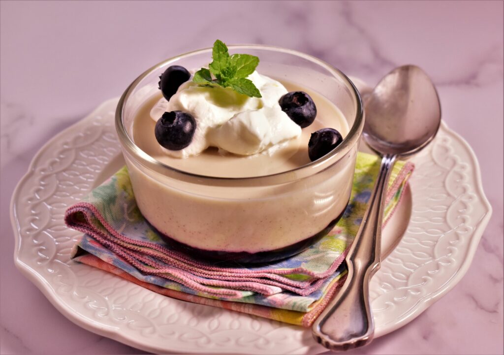 a cup of panna cotta with berry compote on a platter