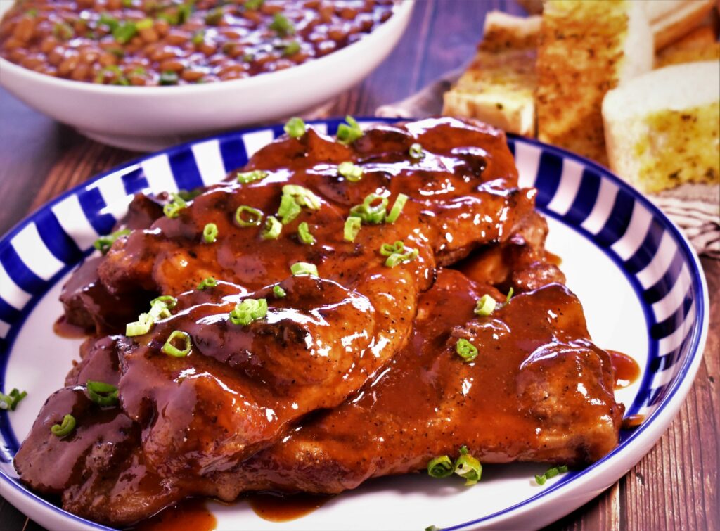 a plate of st louis styled bbq pork steaks with green onions as garnish