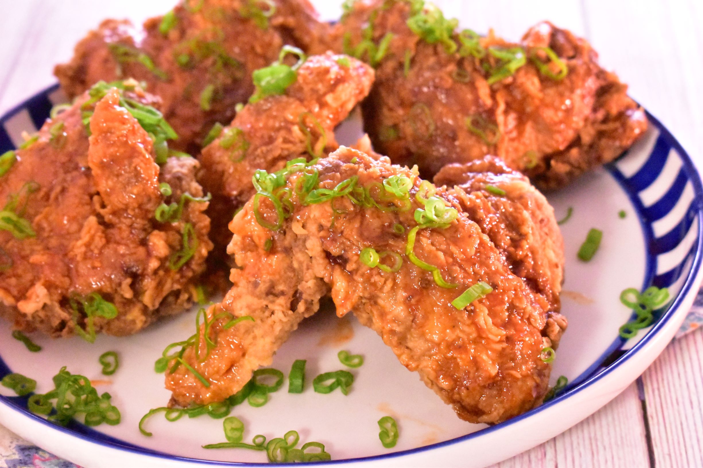 a plate of honey sriracha wings with green onions as garnish