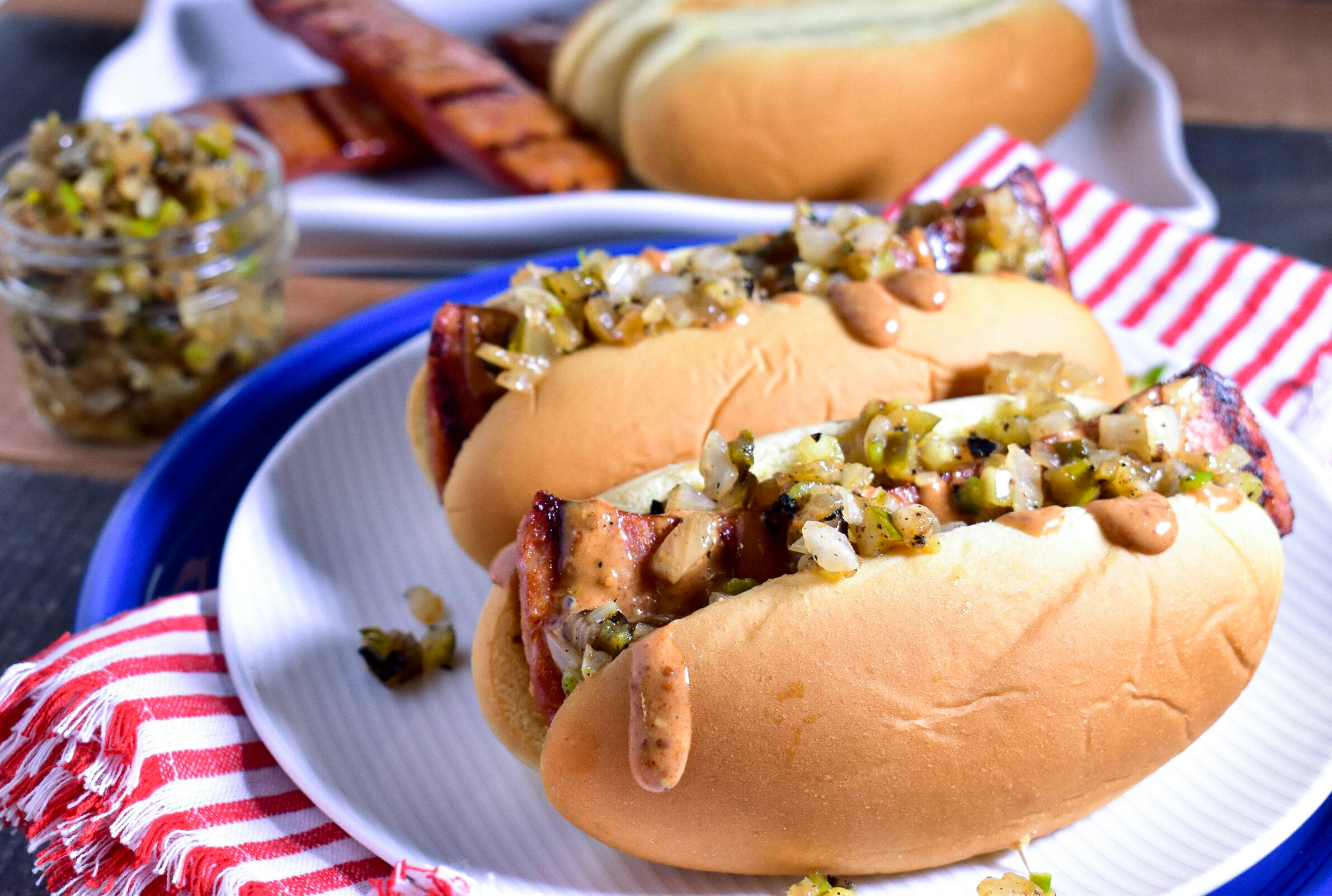 a plate of 2 grilled andouille dogs with jalapeno relish on top