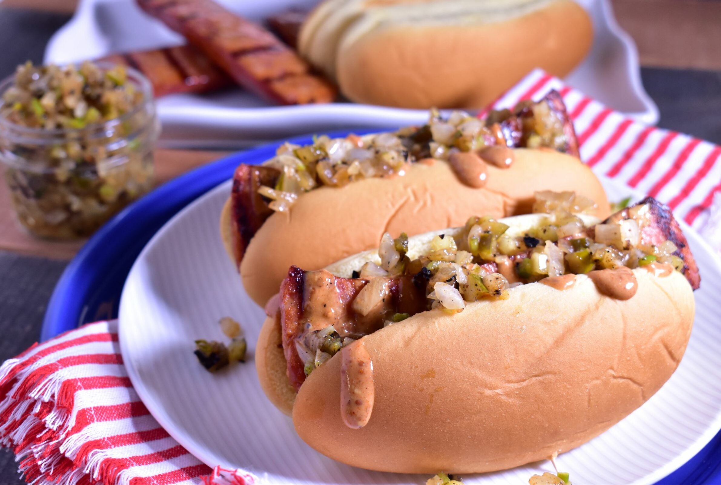 a plate of 2 grilled andouille dogs with jalapeno relish on top