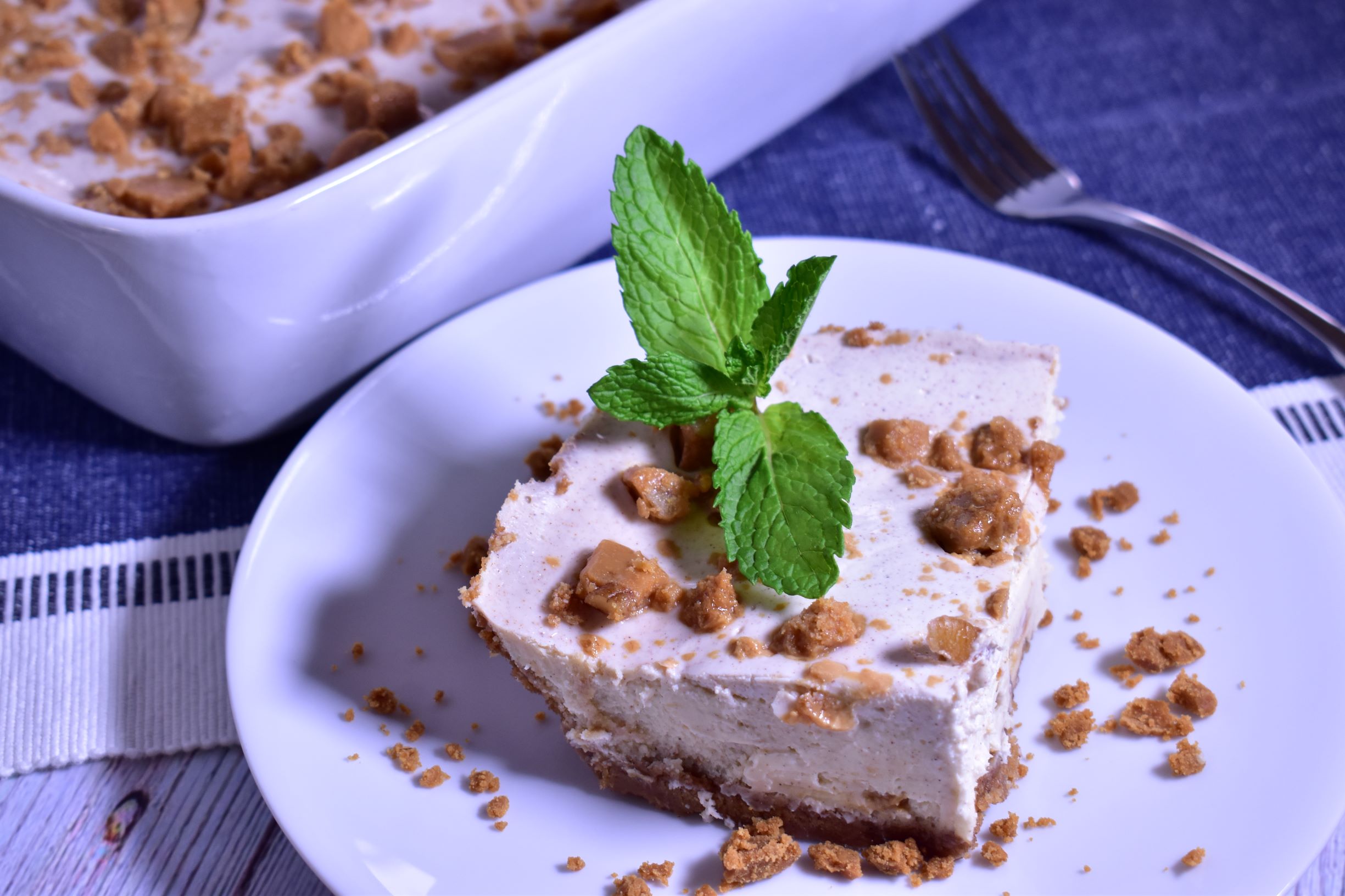 a piece of praline cheesecake with a green garnish next to a dish of the praline cheesecake it came from