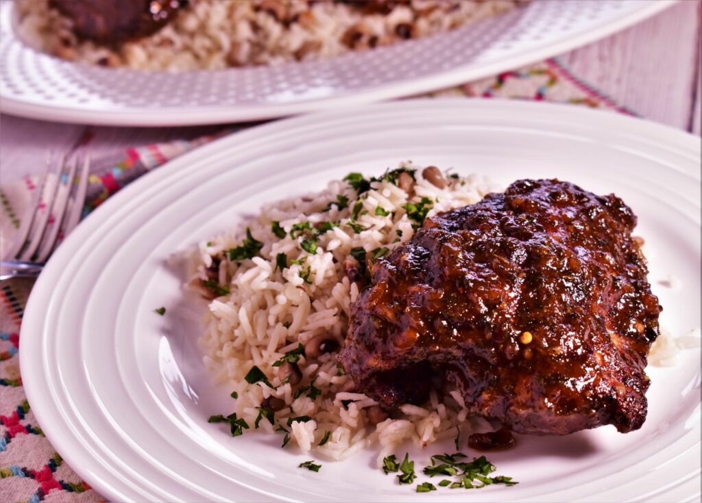 a plate of sticky bbq jerk chcken and a side of rice with cilantro