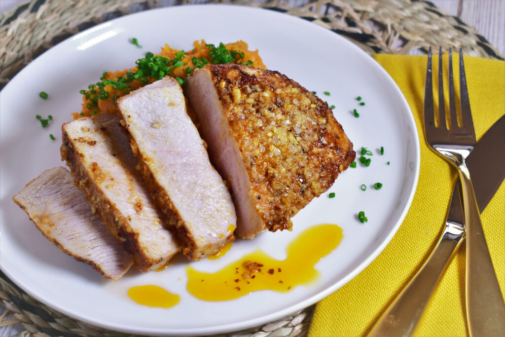 a plate of air fryer pork chops, cut into 4 pieces, with a garlic ginger butter sauce topped with green onions