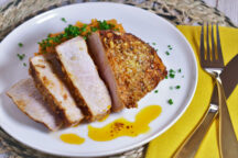 a plate of air fryer pork chops, cut into 4 pieces, with a garlic ginger butter sauce topped with green onions