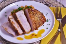 a plate of air fryer pork chops, cut into 4 pieces, with a garlic ginger butter sauce topped with green onions