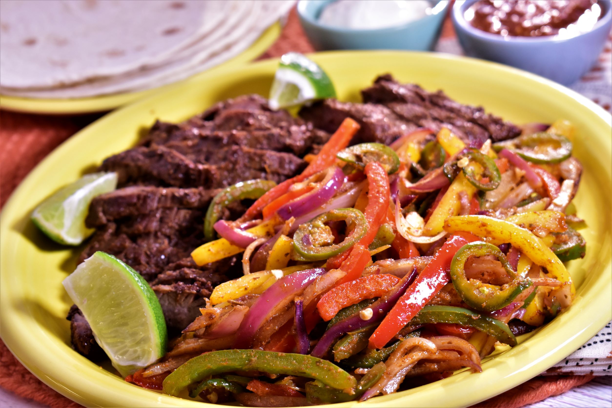 a plate of air fryer steak fajitas with a side of mexed vegtables with lime slices for garnish