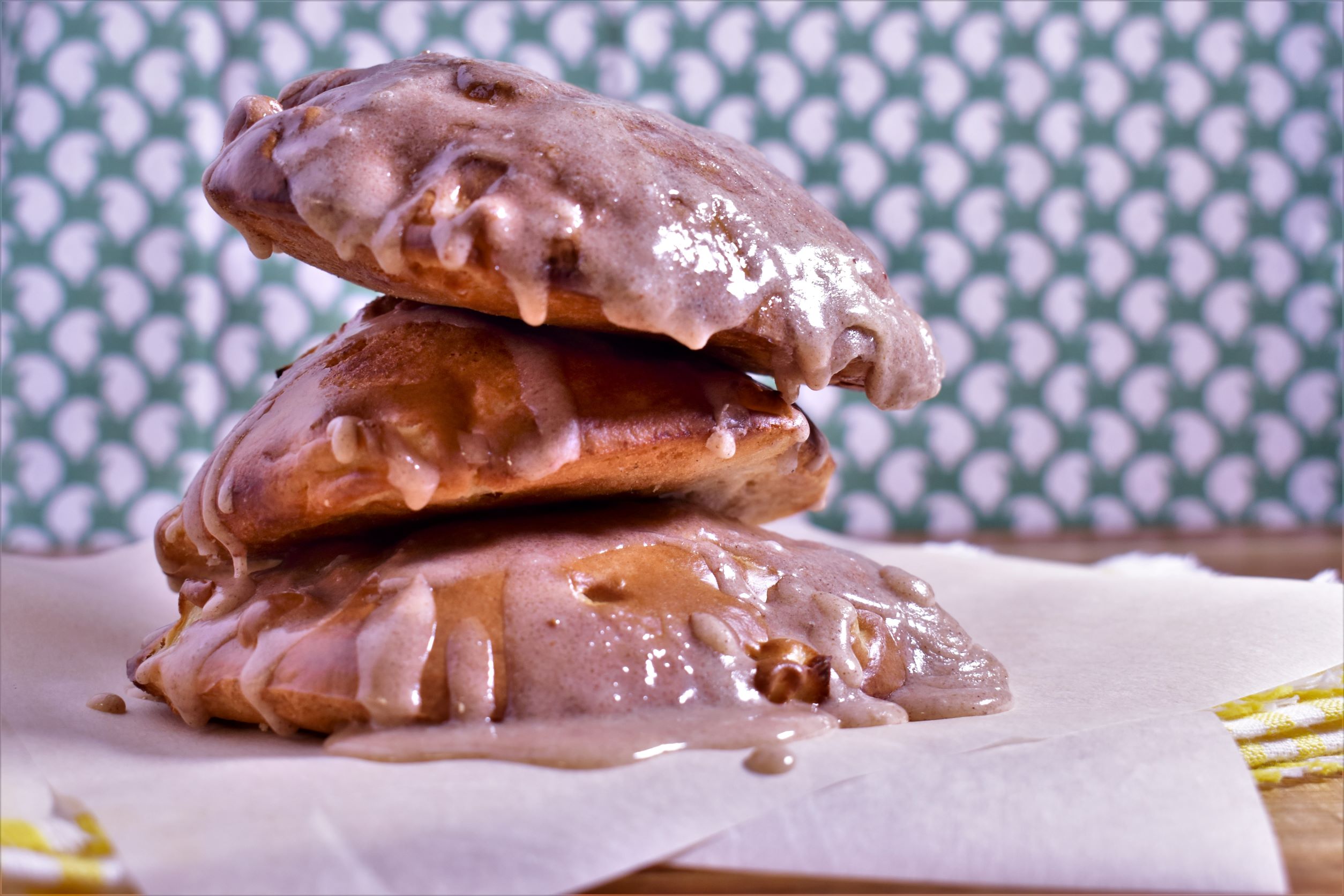 3 Pieces of air fryer apple fritters stacked on top of eachother, drizzled with frosting