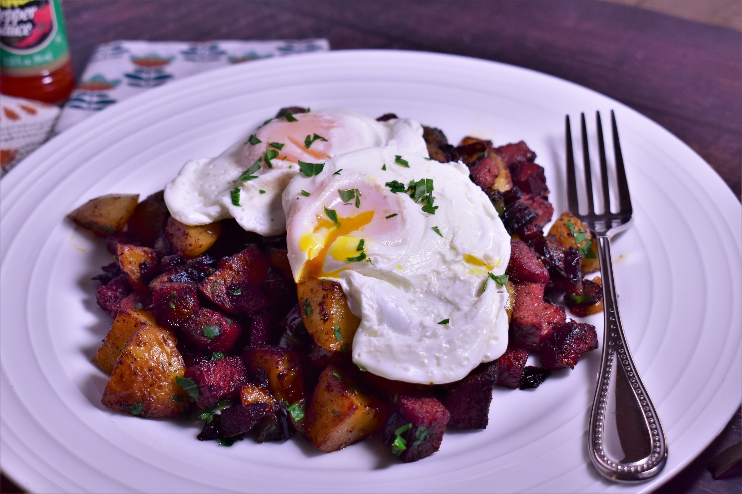 a plate of corned beef hash topped with a dallop of sour cream and cilantro