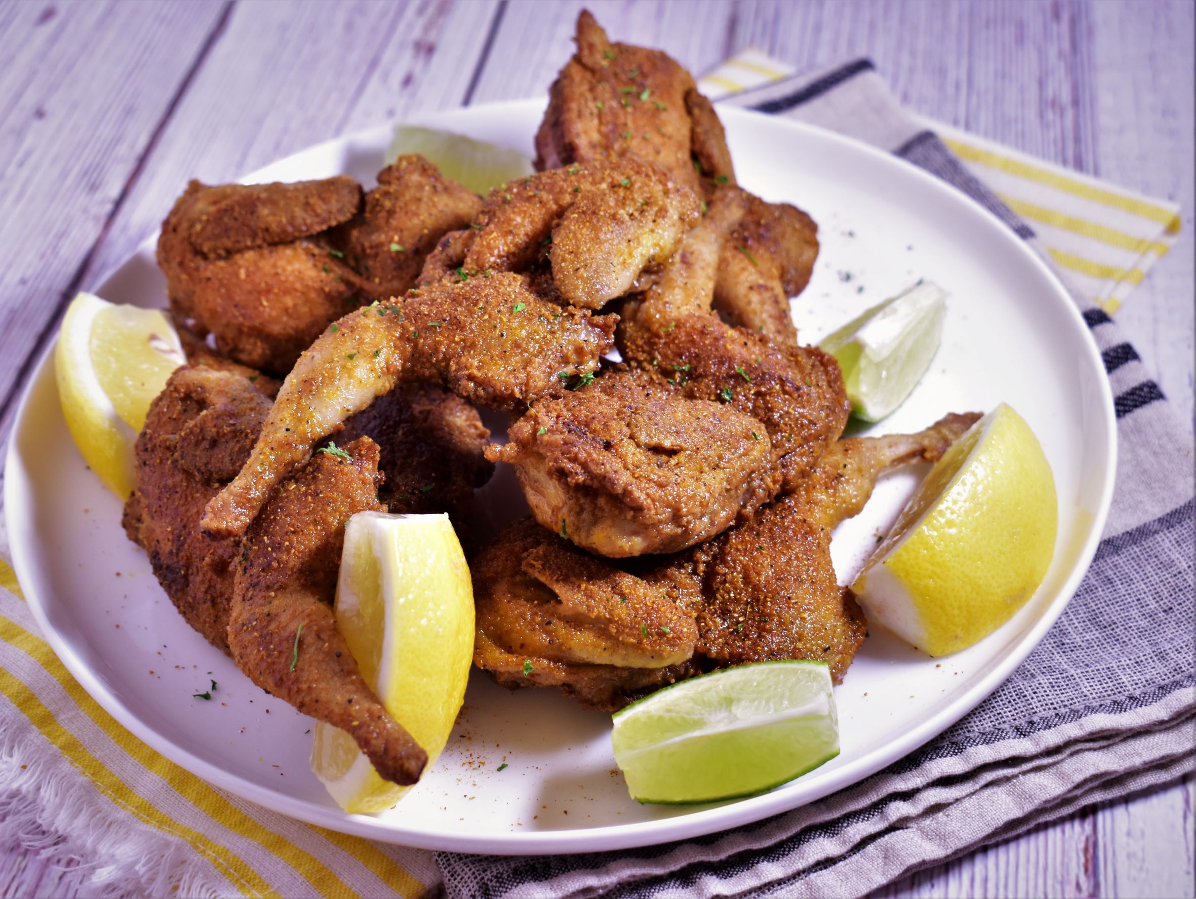 A plate of curry dusted quail with lemon and lime slices