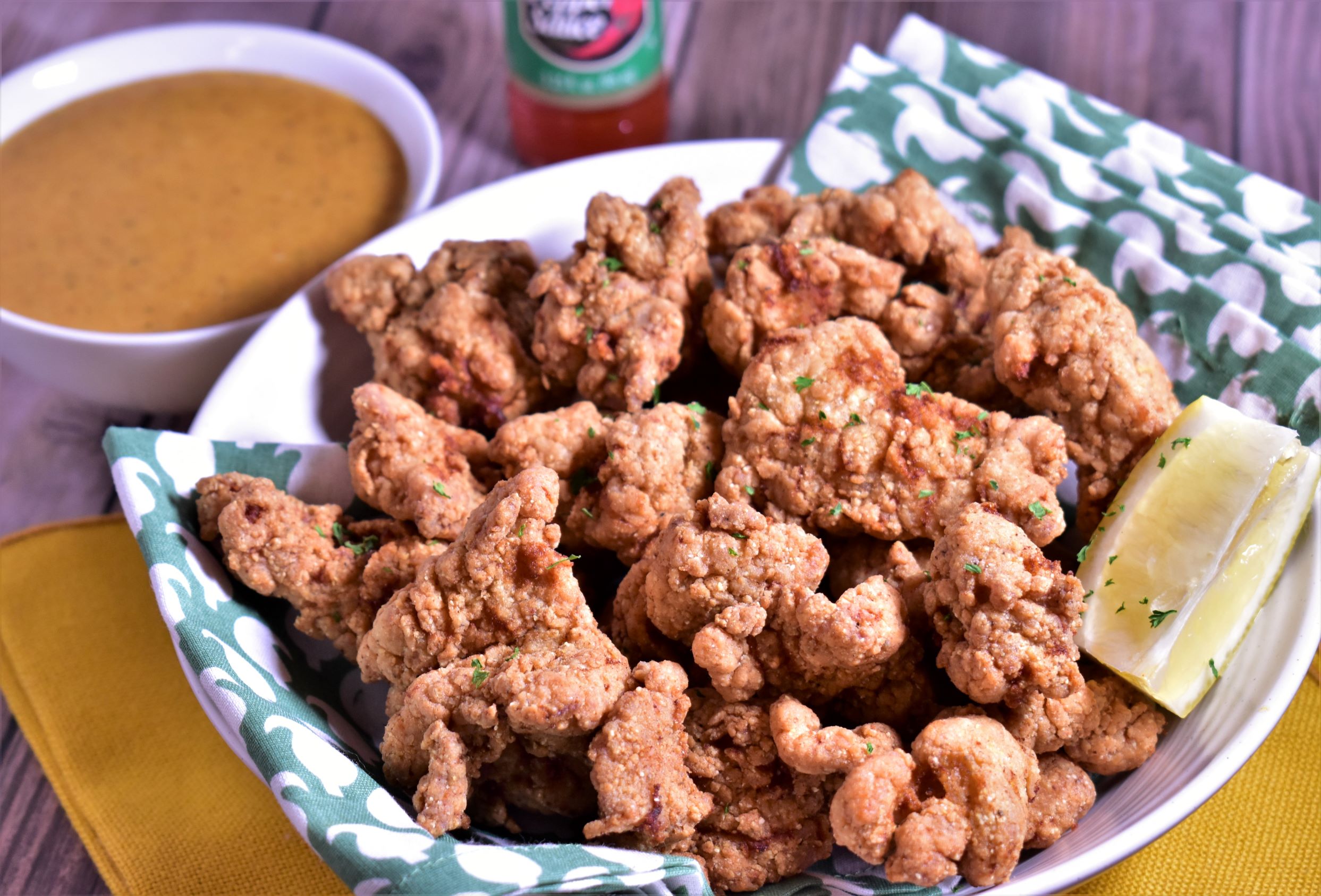 a plate full of fried aligator with a slice of lemon and dipping sauce on the side