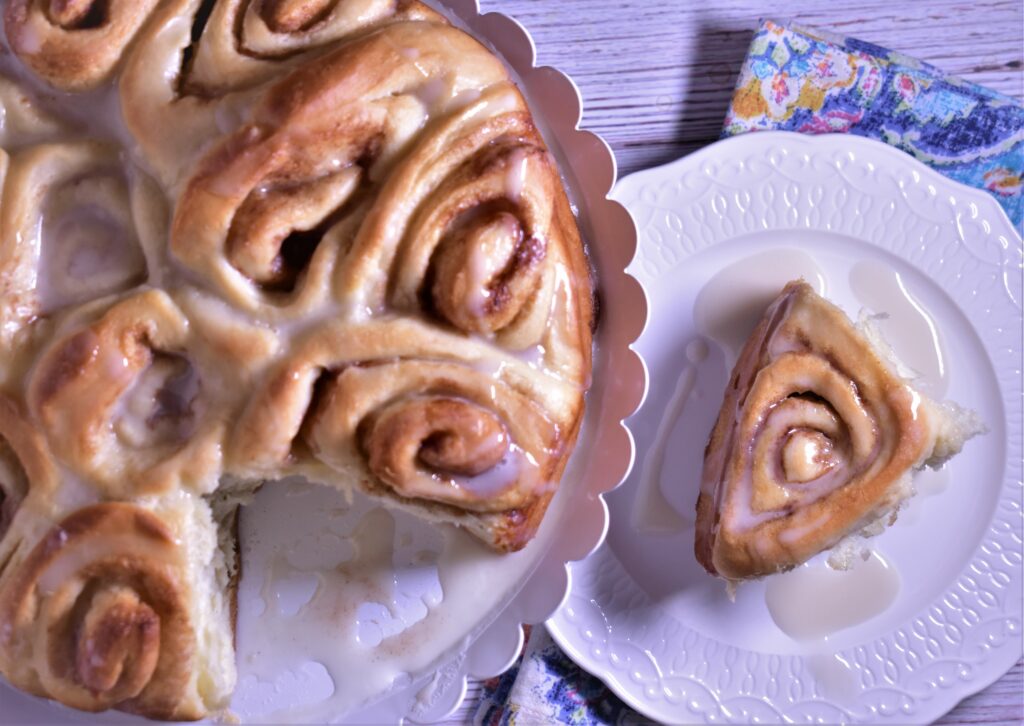 A piece of pull apart cinnamon rolls on a plate next to a plate full of pull apart cinnamon rolls