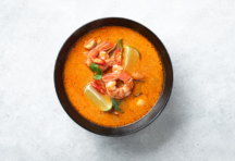 Bowl of soup with shrimp, limes and herbs