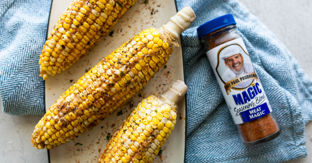 Griller corn on the cob on a platter with a bottle of Meat Magic to the side