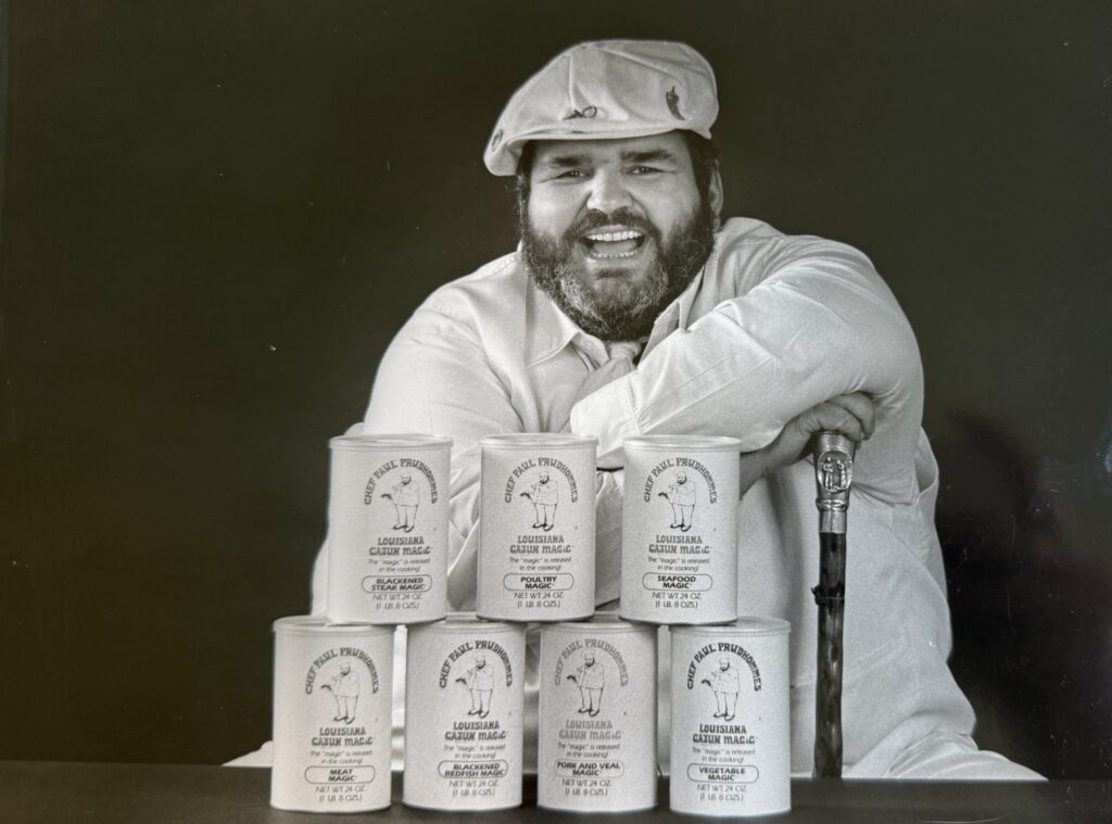 Chef Paul sitting behind 6 cans of Louisiana Cajun Magic