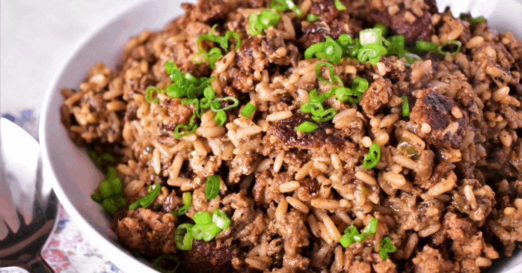 Bowl of Dirty Rice topped with chopped green onions.