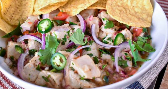 A colorful bowl of ceviche and mixed vegetables served with crunchy tortilla chips on the side.