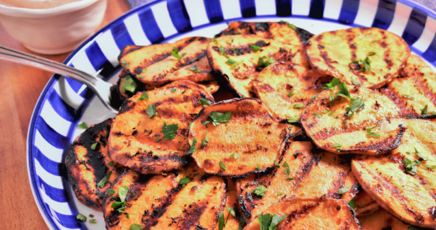 Grilled sweet potatoes arranged on a plate, accompanied by a flavorful dipping sauce for added taste.