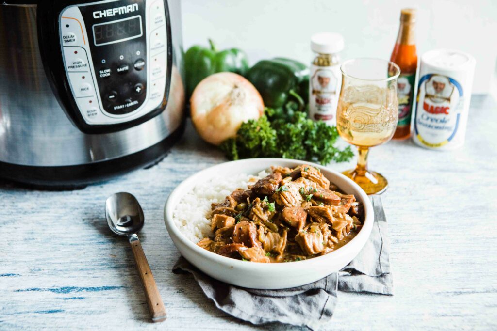 Gumbo with rice in a white bowl next to a spoon and an instant pot
