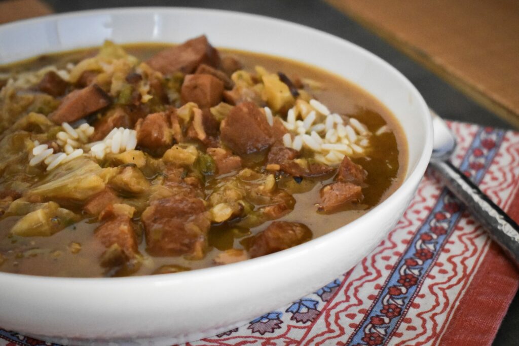 Gumbo in a white bowl on top a red and blue kitchen towel