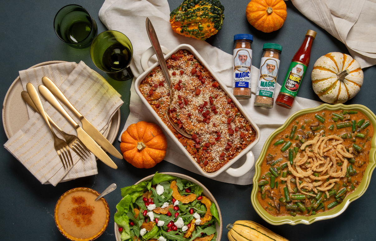 A festive autumn meal featuring dishes in bowls: a bean casserole with breadcrumbs, a green bean dish with crispy onions, and a salad with pomegranate seeds. Surrounded by pumpkins, decorative gourds, prepared spices, and drinks. The table setting includes golden utensils and a small pumpkin pie, creating a warm, celebratory tone.